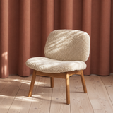 Loungestolen Pandora Lounge med blødt fåreskind, trædetaljer og rustrøde nuancer i et roligt skandinavisk design.