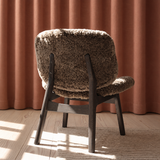 Loungestolen Pandora Lounge med blødt fåreskind, trædetaljer og rustrøde nuancer i et roligt skandinavisk design.